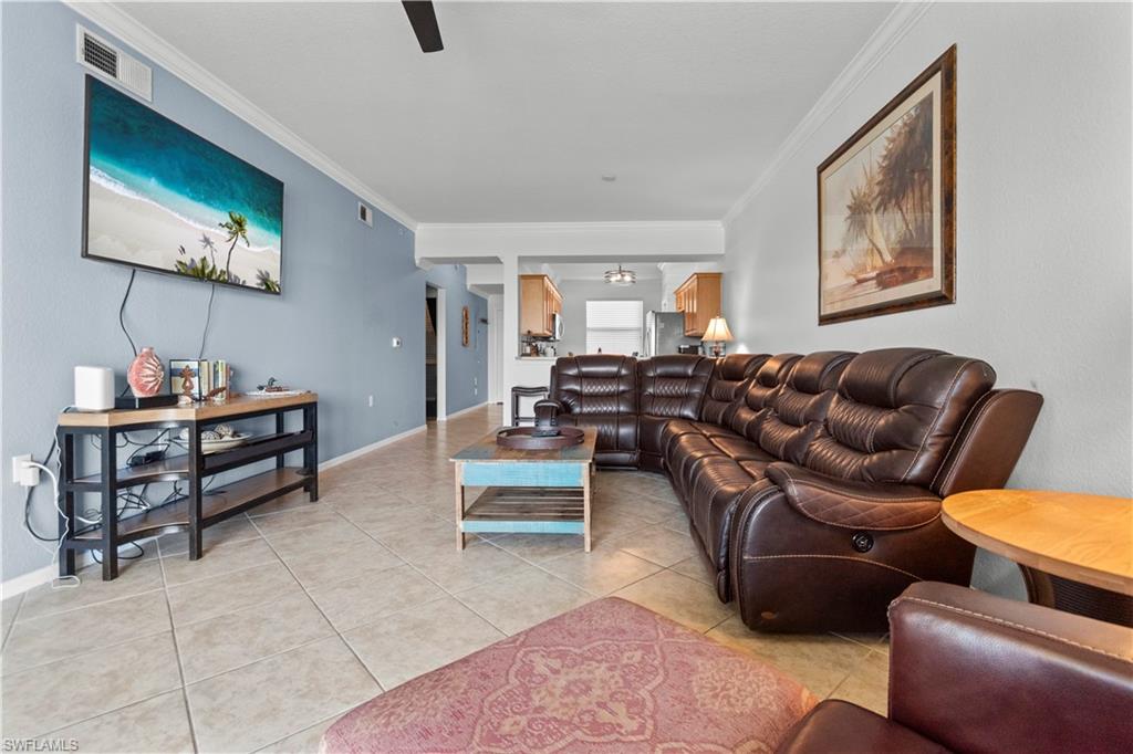 Spacious living area featuring neutral tile flooring and crown molding.