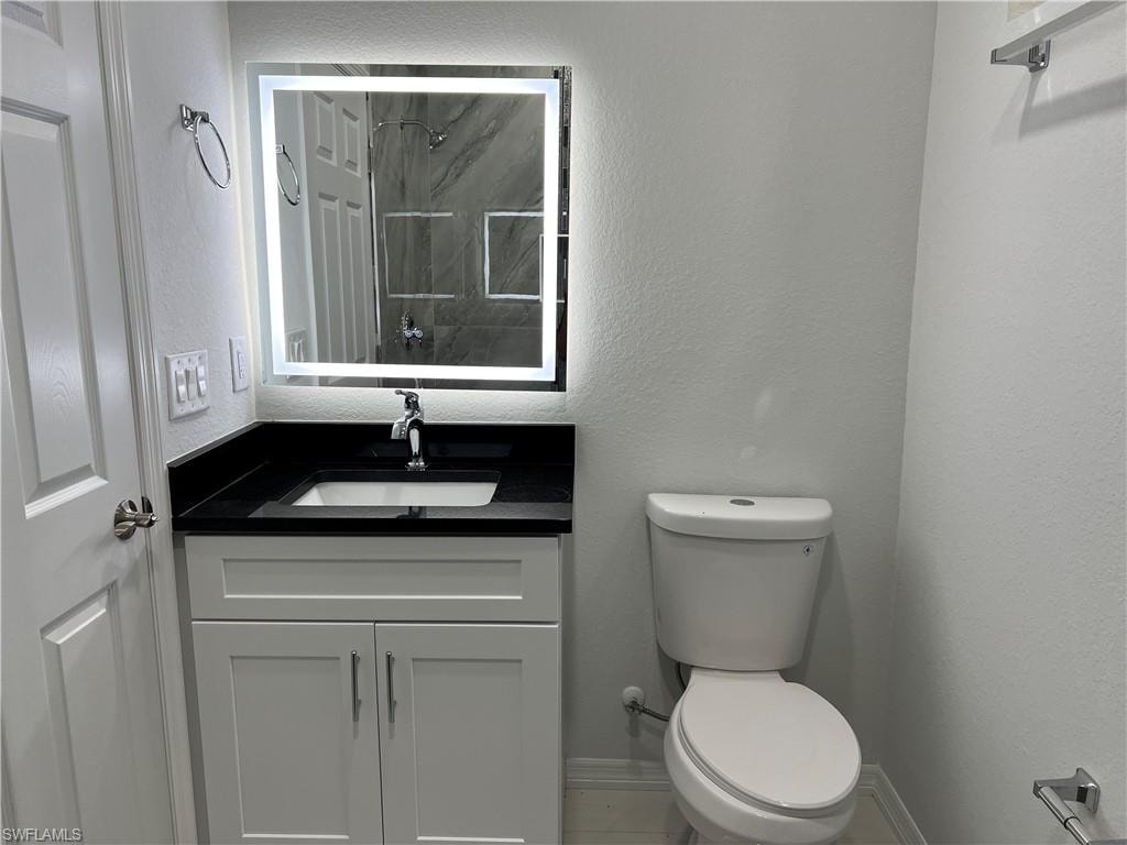 Bathroom featuring a modern vanity with a white shaker-style cabinet, a black countertop, and an integrated sink