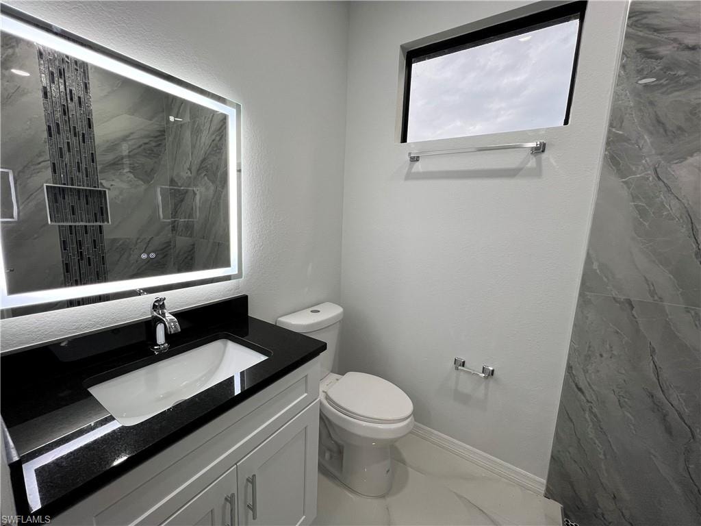 Bathroom featuring a white vanity with a black countertop, undermount sink, and chrome faucet
