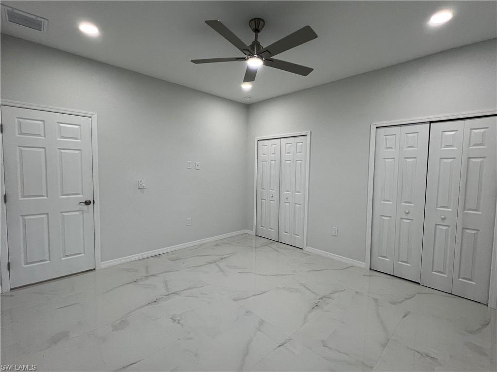 Spacious room featuring large format tile flooring, a contemporary ceiling fan, recessed lighting, white interior doors, and white bi-fold closet doors