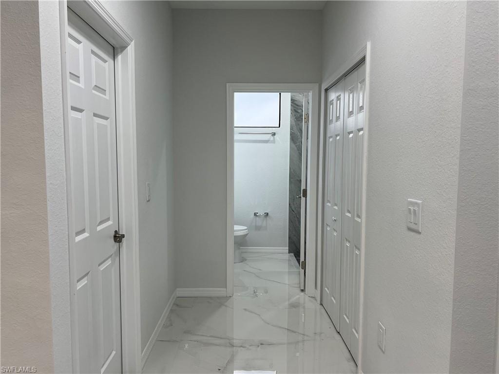 Hallway featuring sleek tile flooring, white baseboards, and neutral wall tones