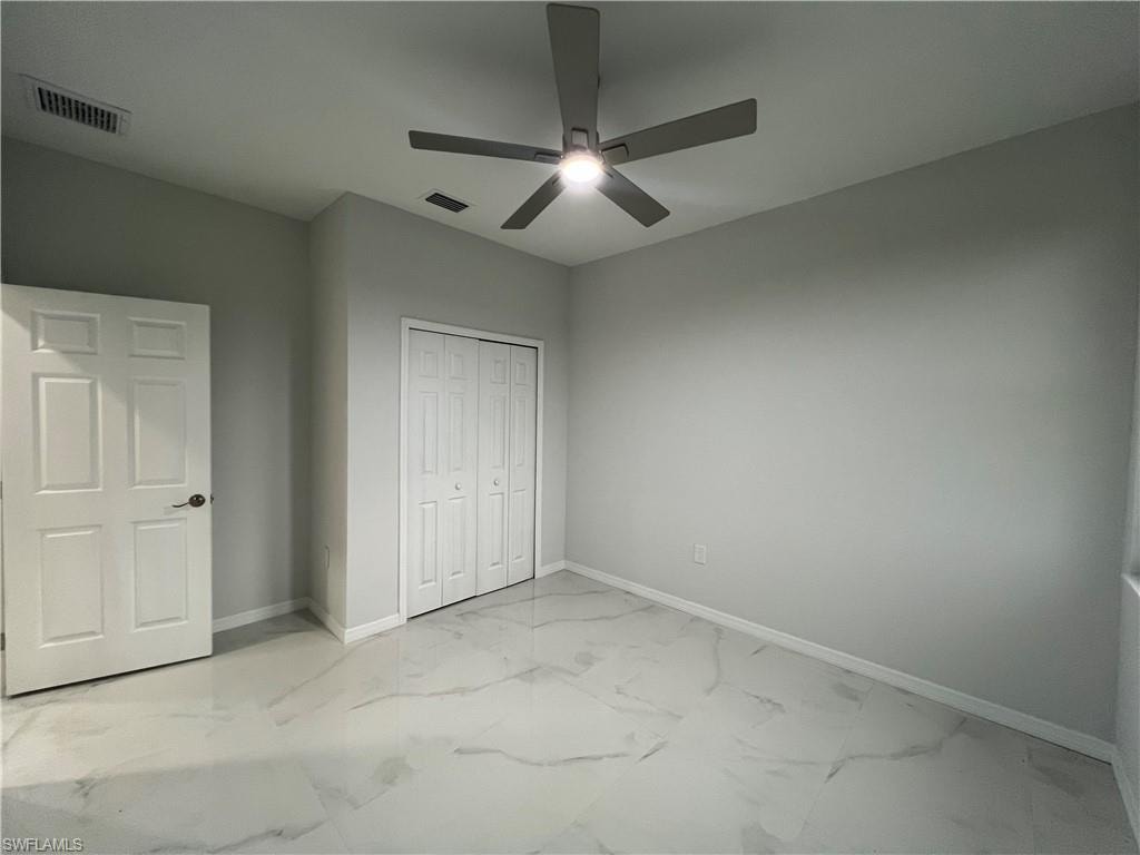 Spacious room featuring modern tile flooring, neutral wall tones, a ceiling fan with integrated lighting, and a bi-fold closet