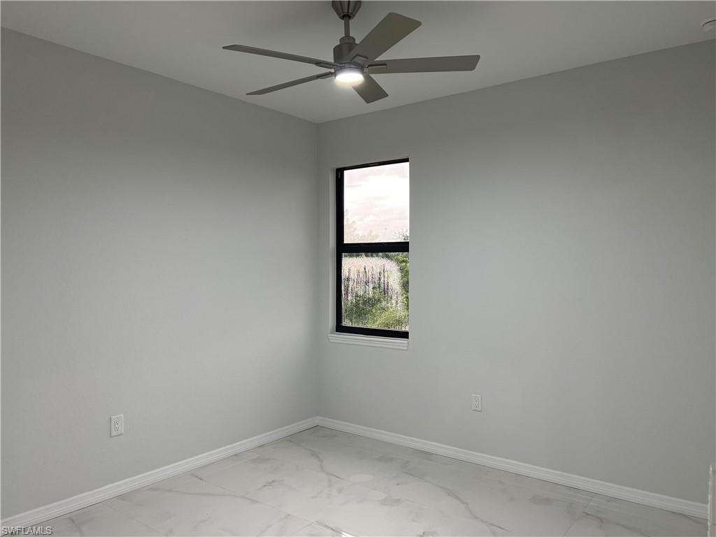 Light-filled room featuring a modern ceiling fan with integrated lighting, a single window with black trim, light gray walls, and white baseboards