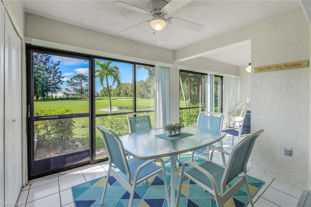Screened patio featuring large sliding glass doors, white tile flooring, ceiling fan, and views of the golf course and pond
