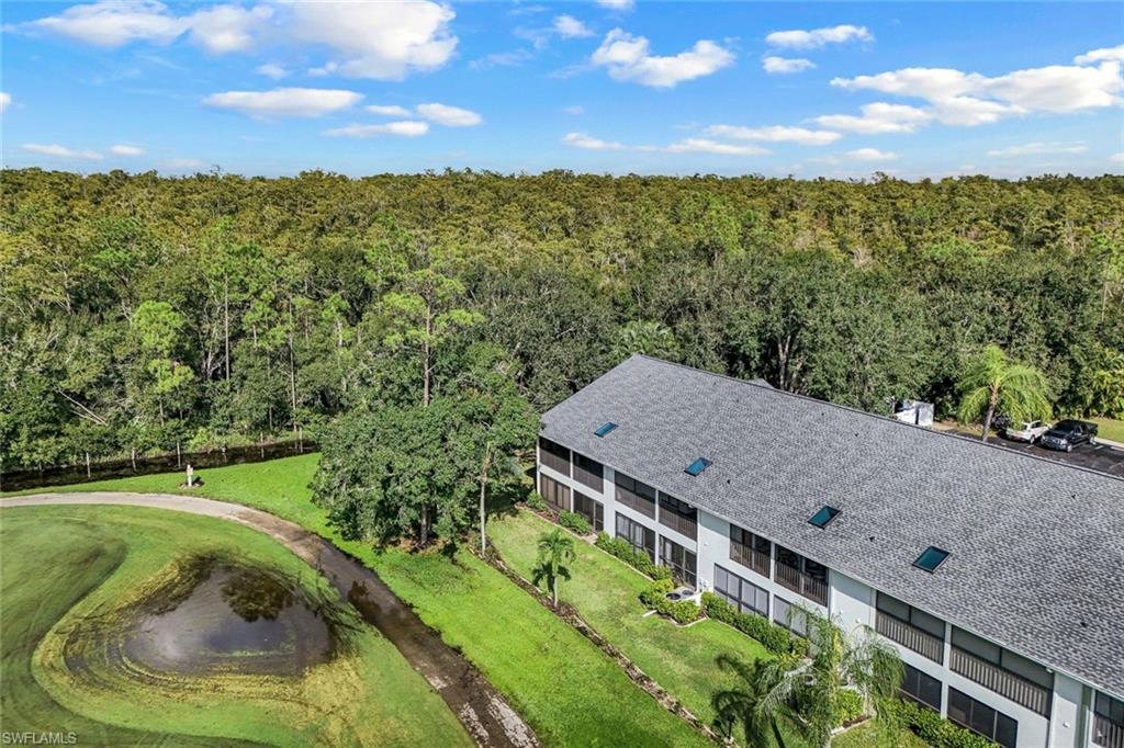 Multi-story building featuring a shingle roof with skylights, multiple screened balconies, and a manicured green lawn