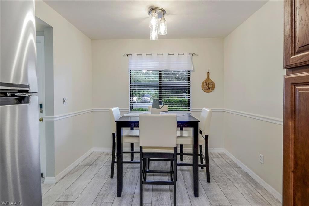 Dining area featuring light wood-finish flooring, a contemporary ceiling light fixture, and a window with blinds