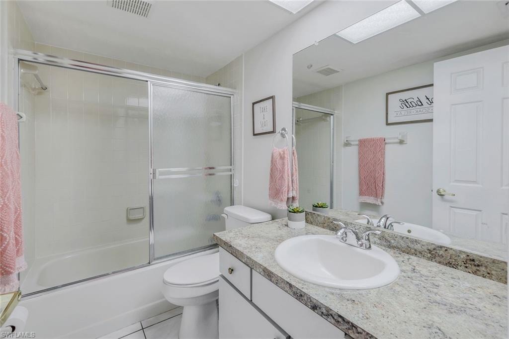 Bathroom featuring a white vanity with an undermount sink, a chrome faucet, and a stone-finish countertop
