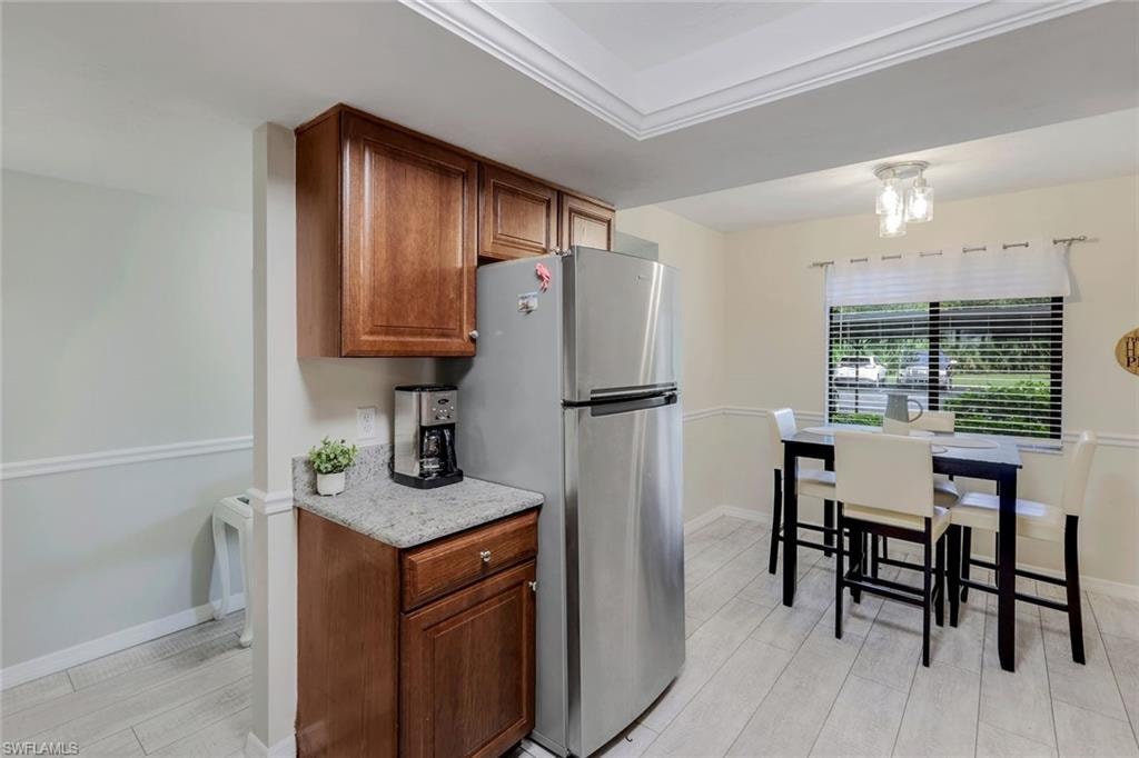 Kitchen area featuring wood-finish cabinetry, light-toned countertops, and stainless steel refrigerator