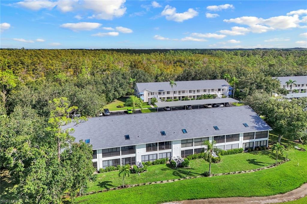 Aerial perspective showcasing multiple multi-story residential buildings with gray shingle roofs, surrounded by extensive green landscaping and mature trees