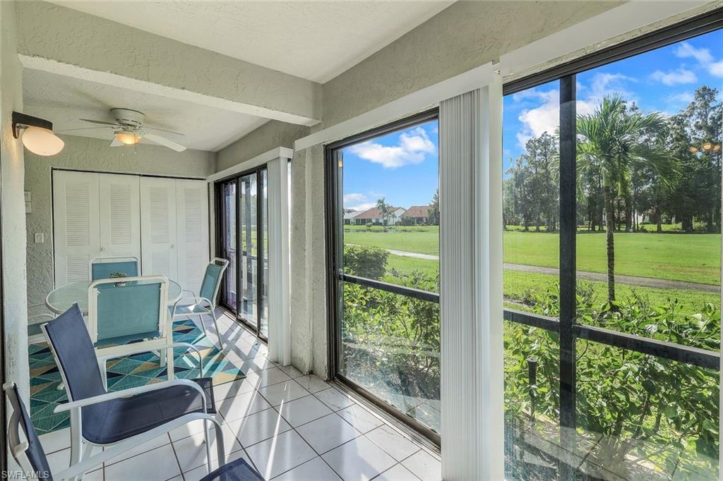 Screened-in porch with white tile flooring, ceiling fan, and louvered bifold doors