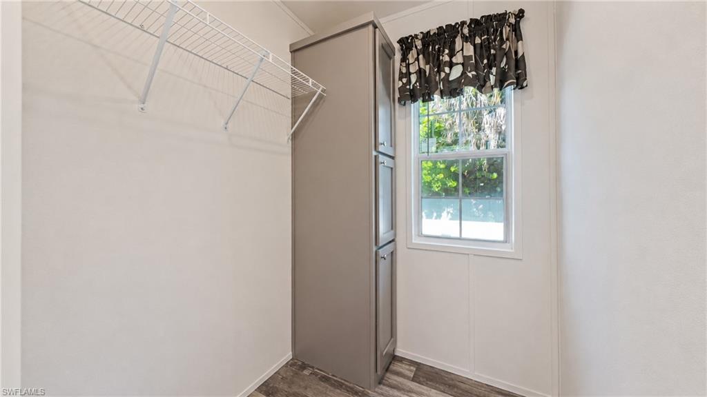 Wardrobe area featuring wire shelving, built-in cabinetry, wood-finish flooring, and a window with white trim