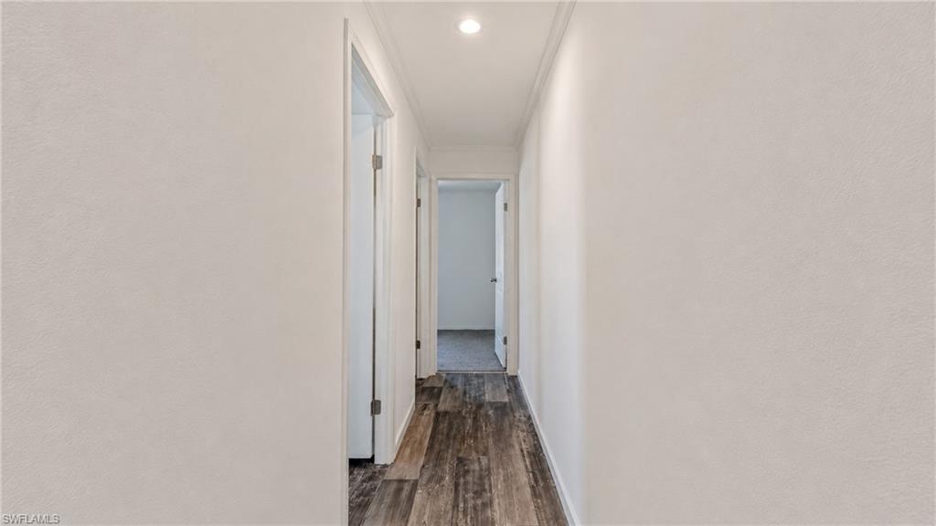 Hallway featuring wood-finish flooring, white painted walls, and recessed lighting
