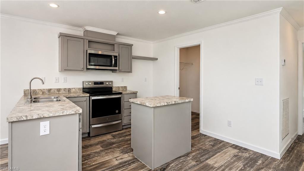 Modern kitchen featuring gray cabinetry, stainless steel appliances, and wood-finish flooring