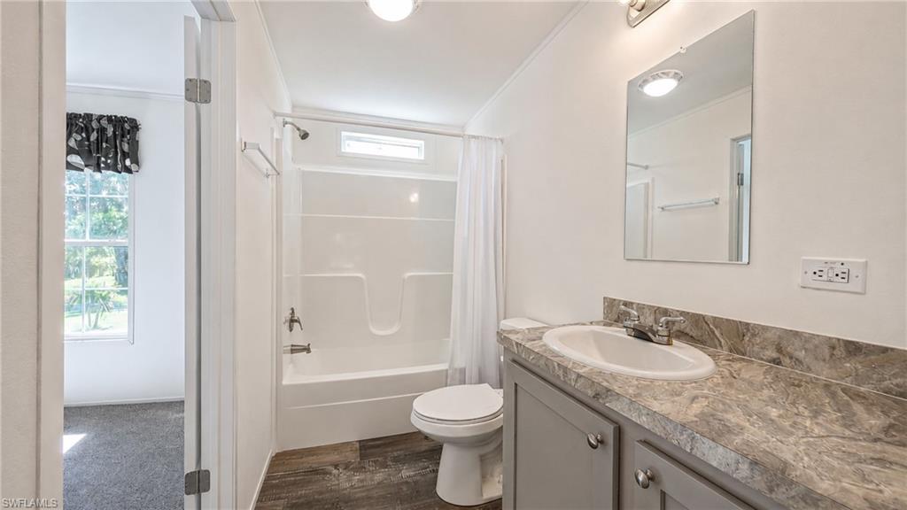 Bathroom featuring a single vanity with gray cabinetry, a white drop-in sink, and a patterned countertop