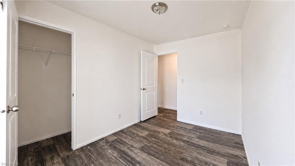 Interior room featuring wood-finish flooring, white painted walls, white trim, and a flush mount ceiling light fixture