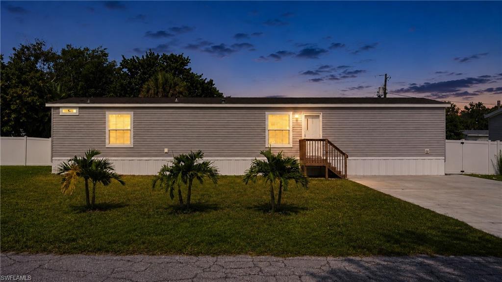 Exterior featuring horizontal siding, a covered entry with wood stairs, multiple windows, and a white fence enclosing the property