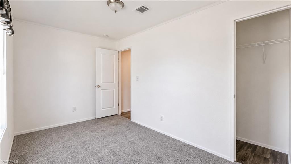 Carpeted room featuring a window, white interior door, and a closet with wire shelving