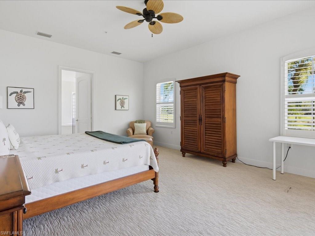 Bright interior space featuring a ceiling fan, white walls, and light-toned carpet flooring