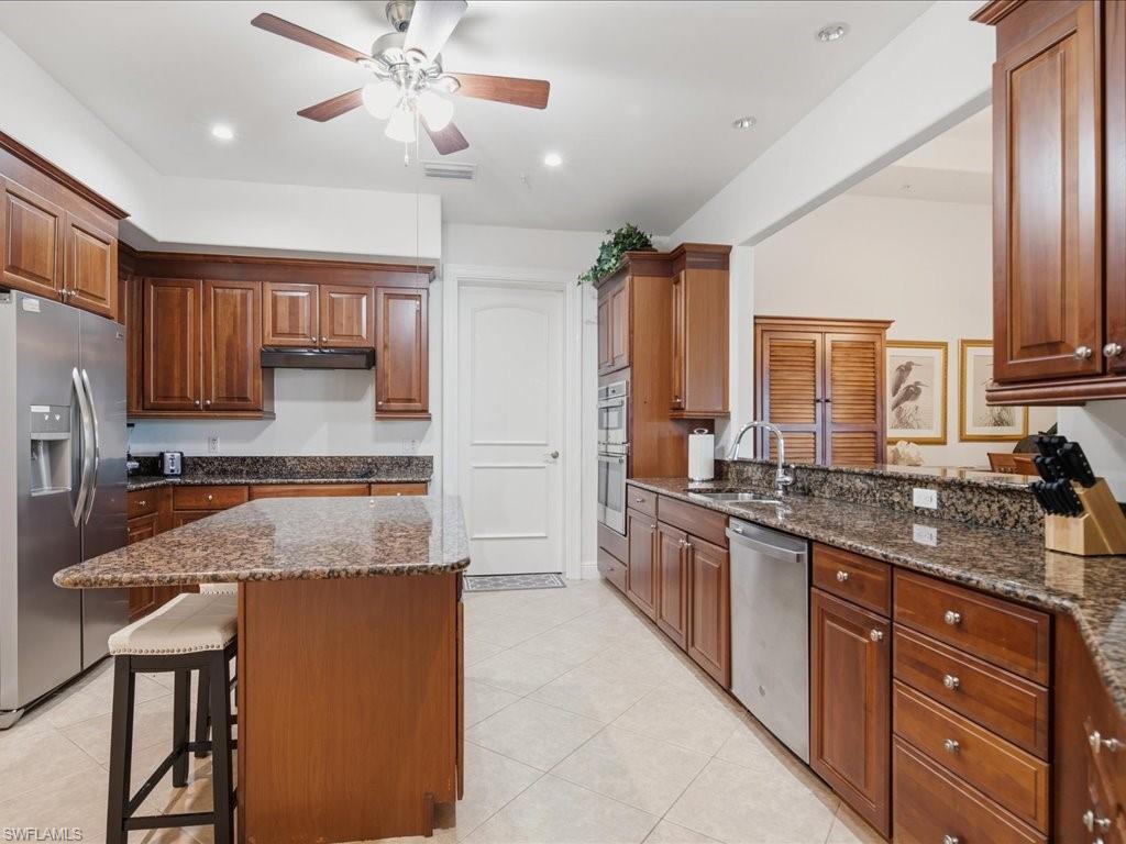 Kitchen featuring wood cabinetry, stainless steel appliances, a center island with seating, granite countertops, and recessed lighting