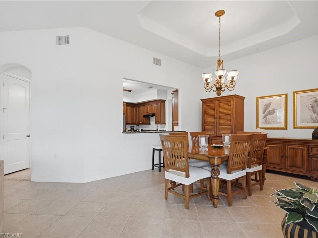 Tray ceiling with a decorative chandelier over tile flooring