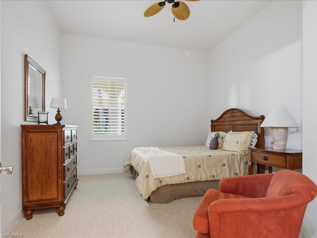 Bright room featuring a window with white louvered blinds, light-toned carpet flooring, a ceiling fan, and white walls