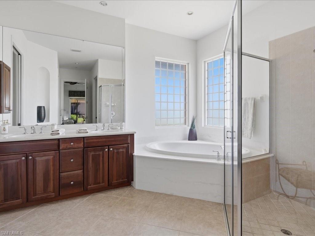Spacious bathroom featuring a double vanity with dark wood cabinetry, an expansive soaking tub, and a glass-enclosed shower