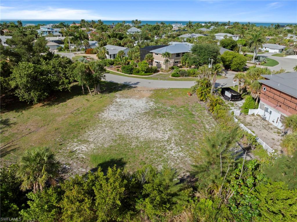 Expansive parcel featuring a clear building site, surrounding mature tropical landscaping, and a distant ocean horizon