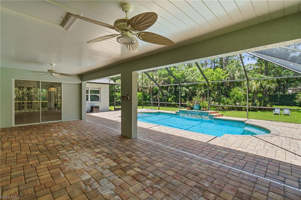 Expansive covered patio featuring brick paver flooring and multiple ceiling fans