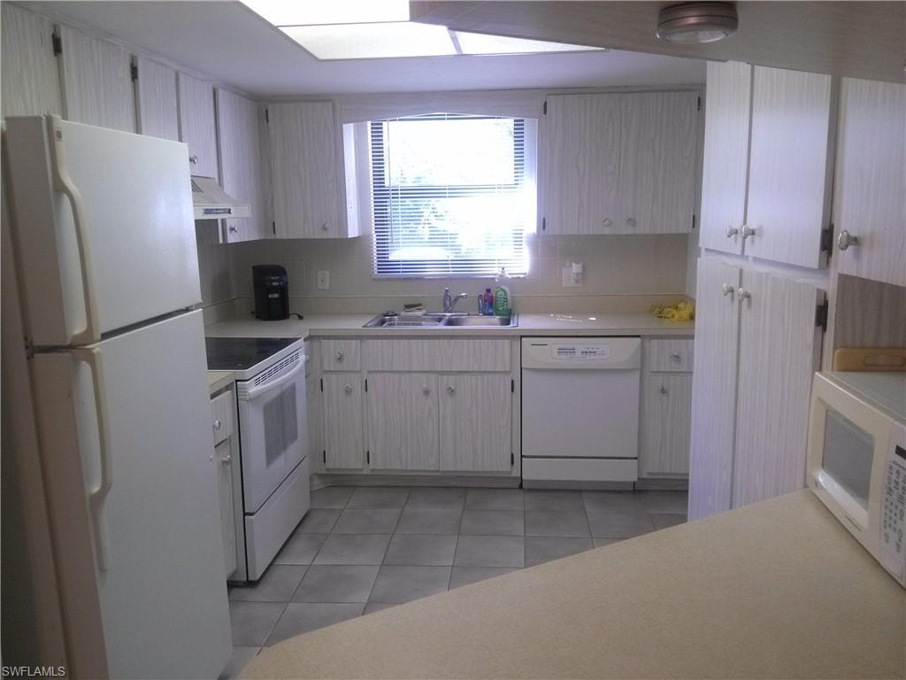 Kitchen with sink, white appliances, light tile floors, and tasteful backsplash