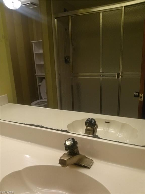 Bathroom with a shower with door, sink, and toilet