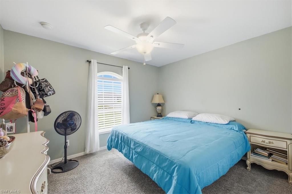 Bedroom featuring an arched window with blinds, a ceiling fan with integrated lighting, and carpet flooring