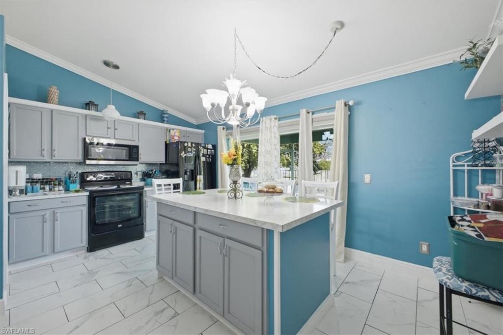 Kitchen featuring light gray cabinetry, a central island with a solid surface countertop, white tile flooring, and vaulted ceilings with crown molding