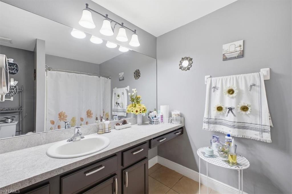 Bathroom featuring a single basin vanity with a light-toned countertop, dark wood-finish cabinetry, and a large wall-mounted mirror