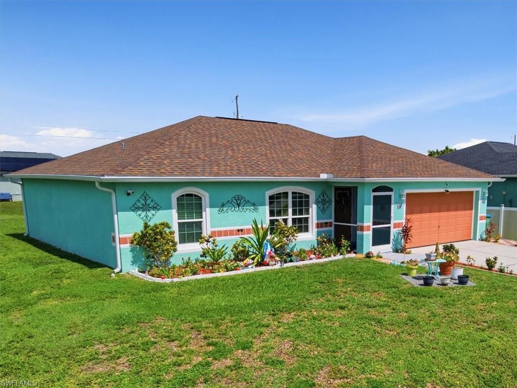 Single-story residence featuring a brown shingle roof, teal stucco exterior, and an orange garage door