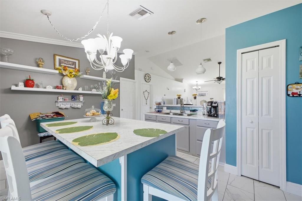 Kitchen featuring a central island with countertop seating, white tile flooring, and vaulted ceilings