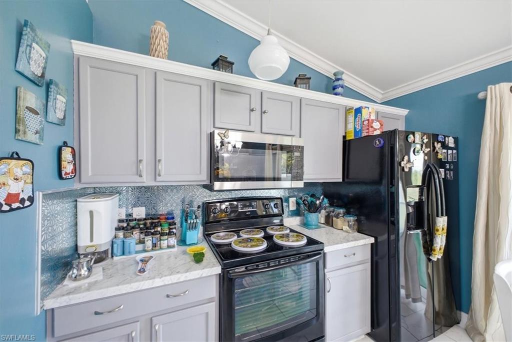 Kitchen featuring light gray cabinetry, light-toned countertops, and a pressed-tin backsplash