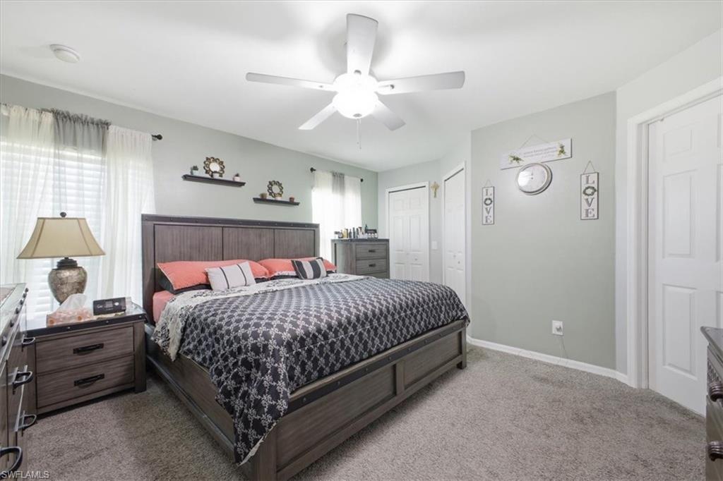 Carpeted room featuring a ceiling fan with integrated lighting, multiple windows with blinds, and white paneled doors