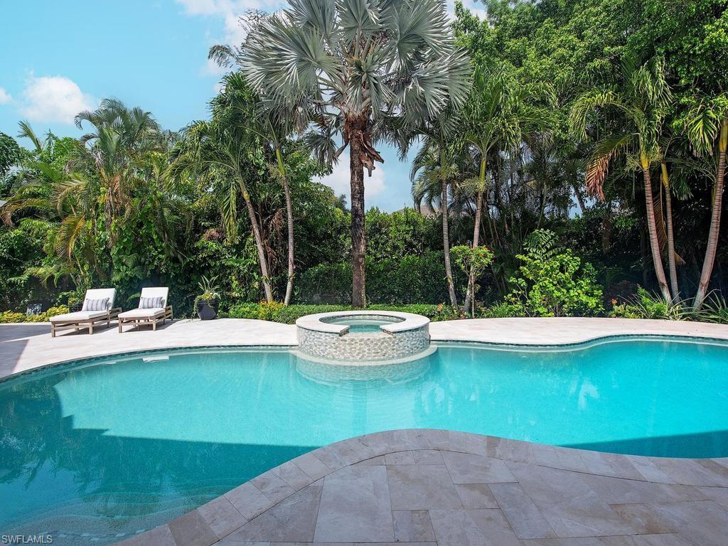 Freeform swimming pool with an integrated circular spa featuring mosaic tile detailing
