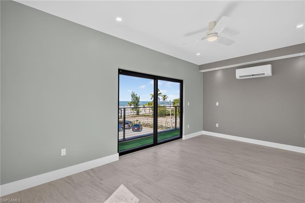 71 Mango Unit 2 Spacious bedroom featuring floor-to-ceiling sliding glass doors, coastal scenery, wood-finish flooring, a ceiling fan, and recessed lighting