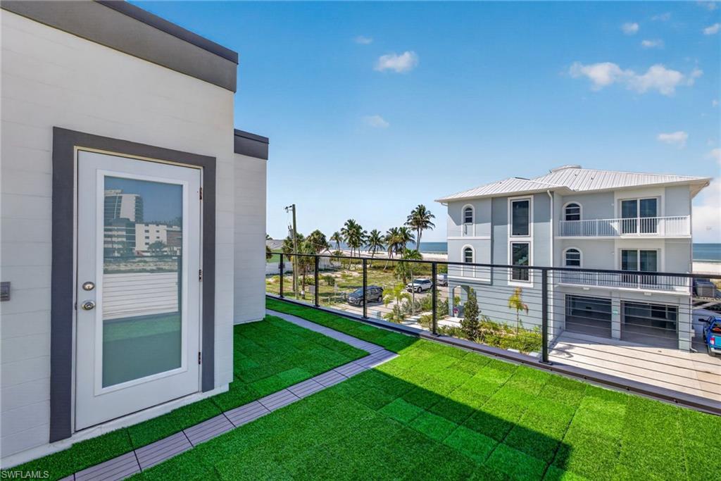 71 Mango Unit 2 Rooftop turf patio with composite tile accents and a glass-paneled door