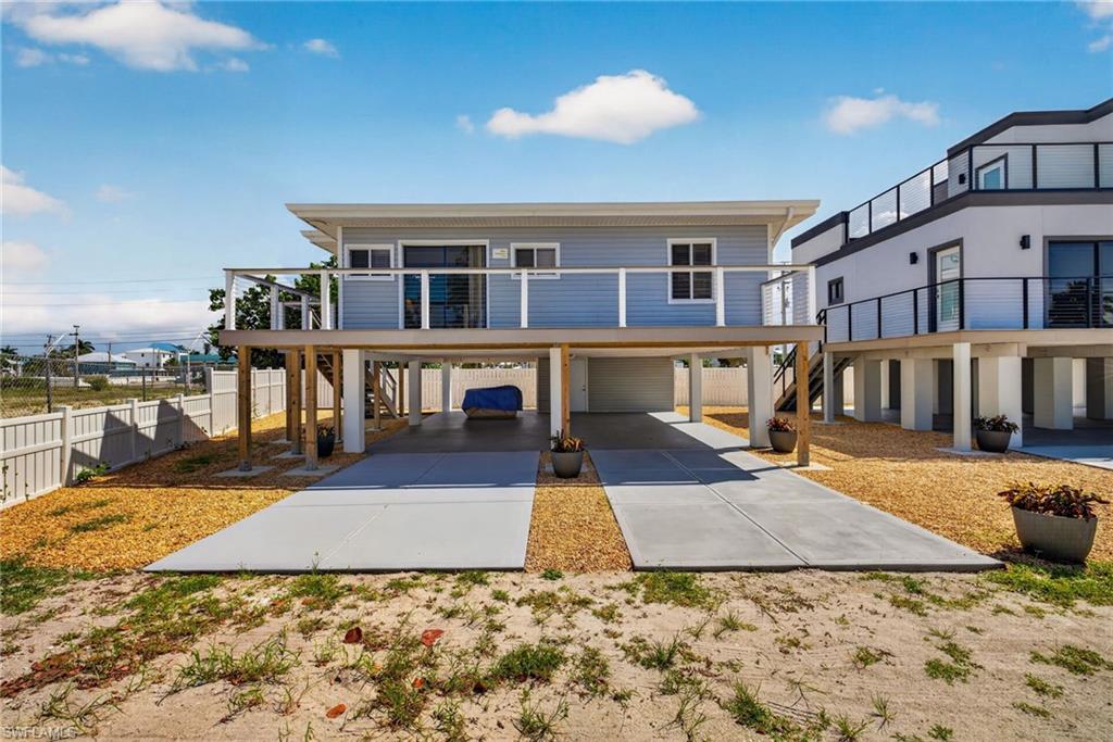 Elevated residence featuring light blue siding and a covered ground-level parking area