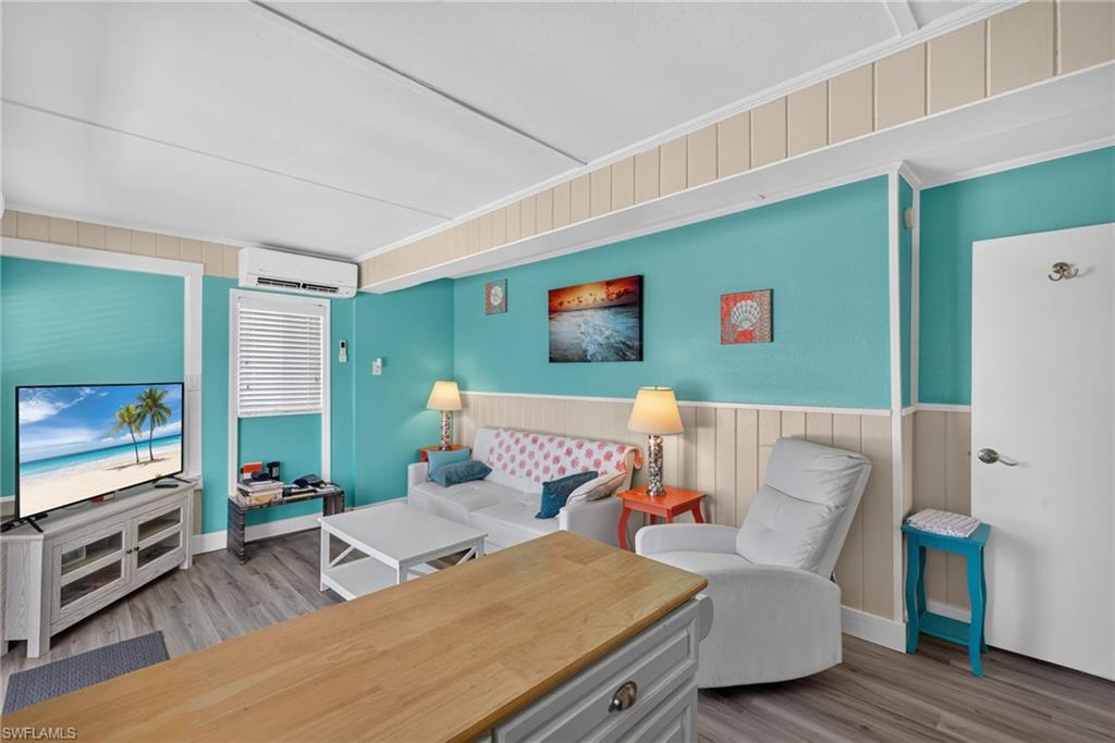 2401 Cottage Ave Unit 2 -  Living area featuring wood-finish flooring, a vibrant turquoise wall accent, and white paneling