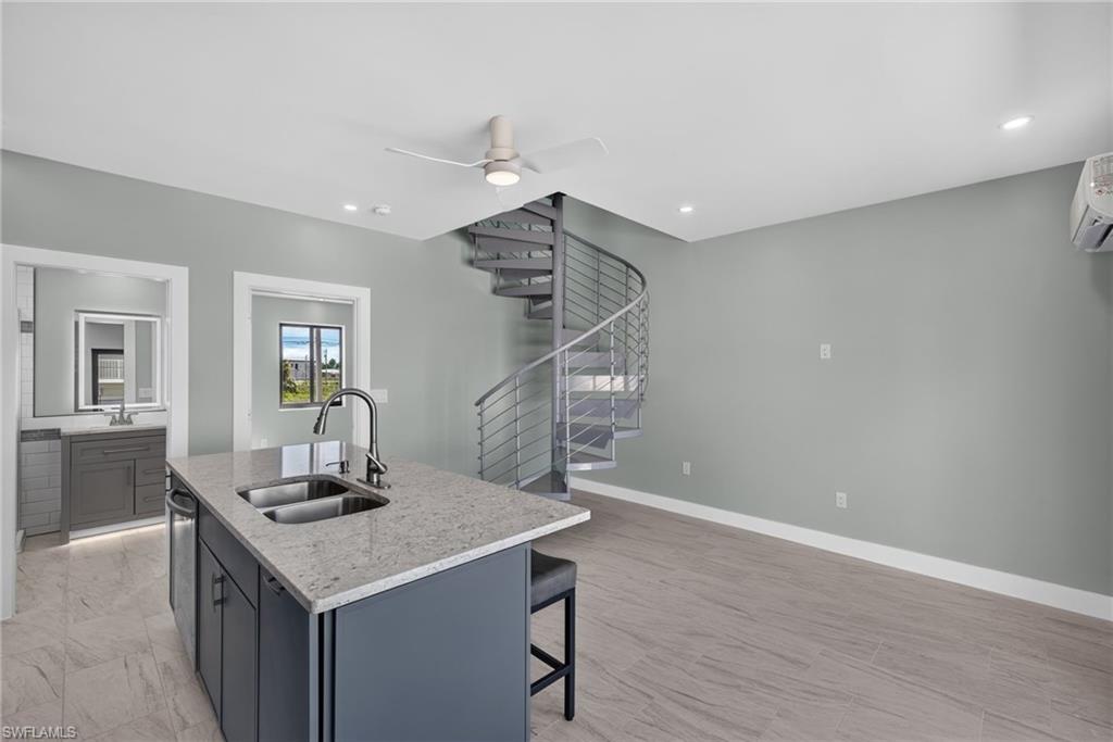 71 Mango Unit 2  Modern kitchen island featuring a dual stainless steel sink, contemporary faucet, and light-toned countertop