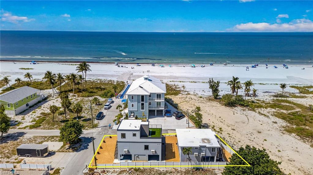 Coastal property featuring a multi-level structure with a flat roof, white exterior, and multiple balconies
