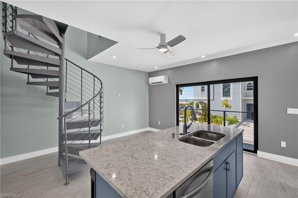 71 Mango Unit 2 Modern kitchen featuring white cabinetry, stainless steel appliances, light-toned countertops, a dual-basin stainless steel sink, and a blue tile backsplash