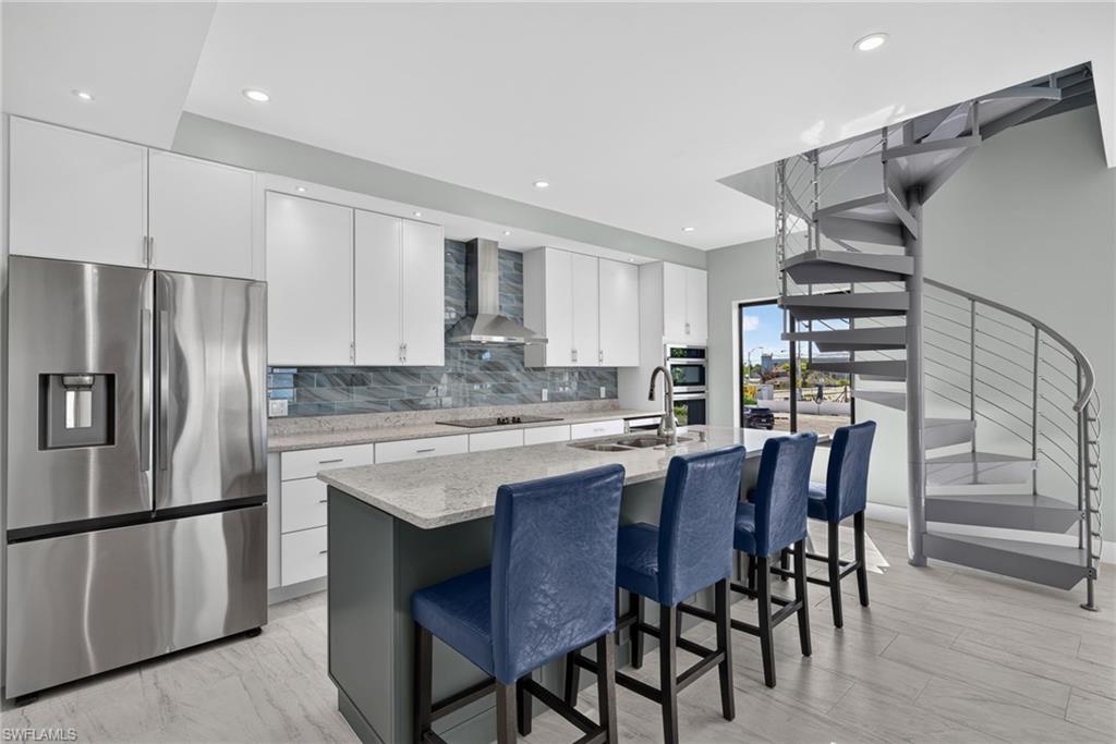 71 Mango Unit 1 Modern kitchen featuring a stainless steel refrigerator, white cabinetry, and a light-colored countertop