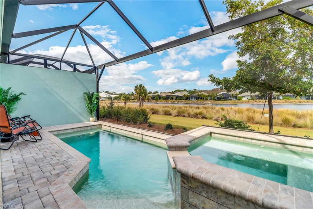 View of pool with a pool with connected hot tub, glass enclosure, and a patio