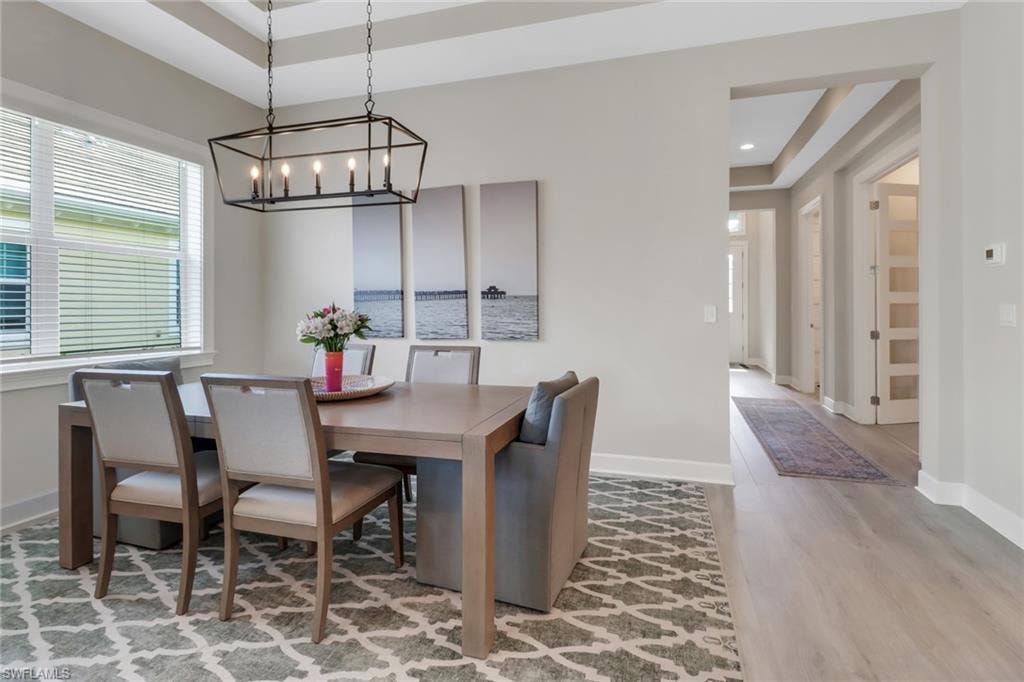 Dining area with recessed lighting, a raised ceiling, baseboards, and wood finished floors