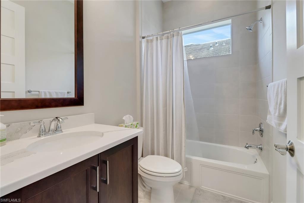 Full bath with tile patterned floors, vanity, toilet, and shower / tub combo with curtain