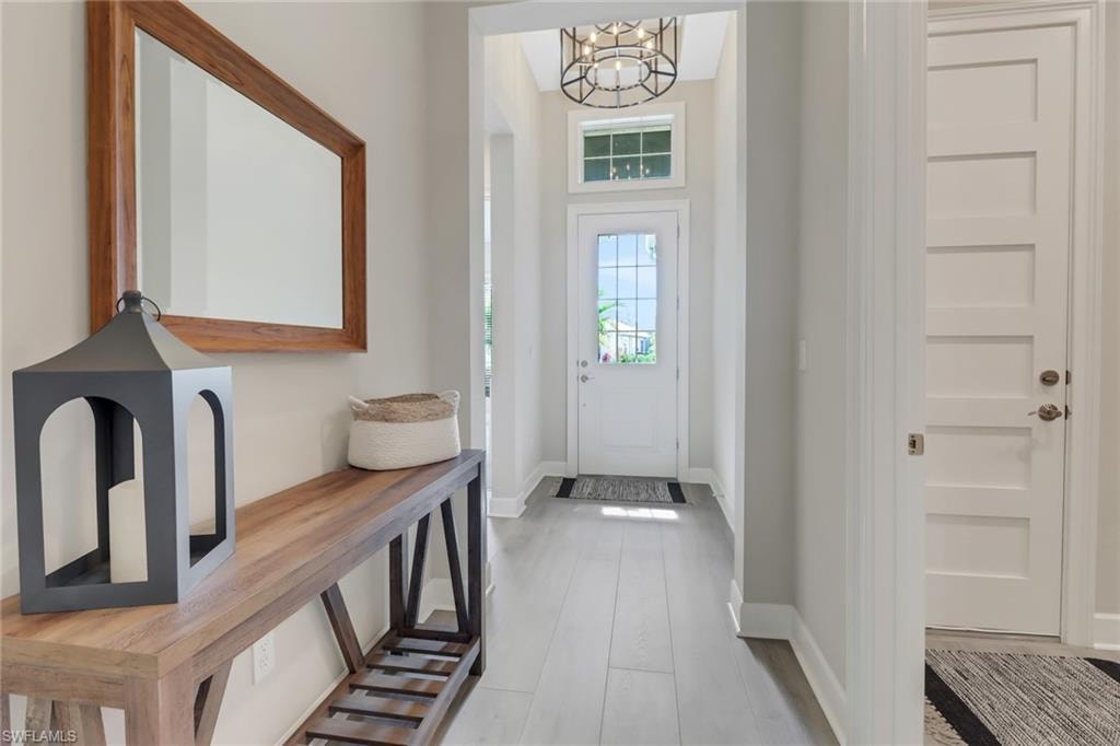 Foyer entrance featuring baseboards, wood finished floors, and an inviting chandelier